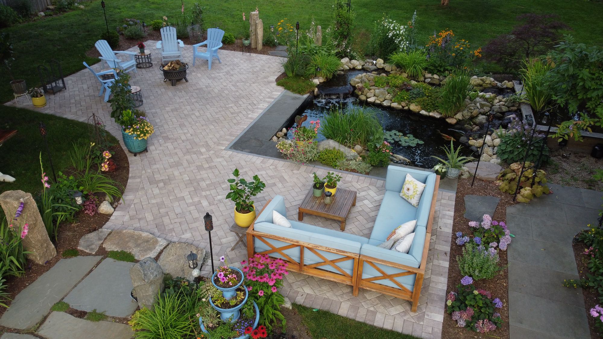 Arnold Ave project; pavers and natural stone with koi pond, sectional, Adirondack chairs and beautiful landscaping