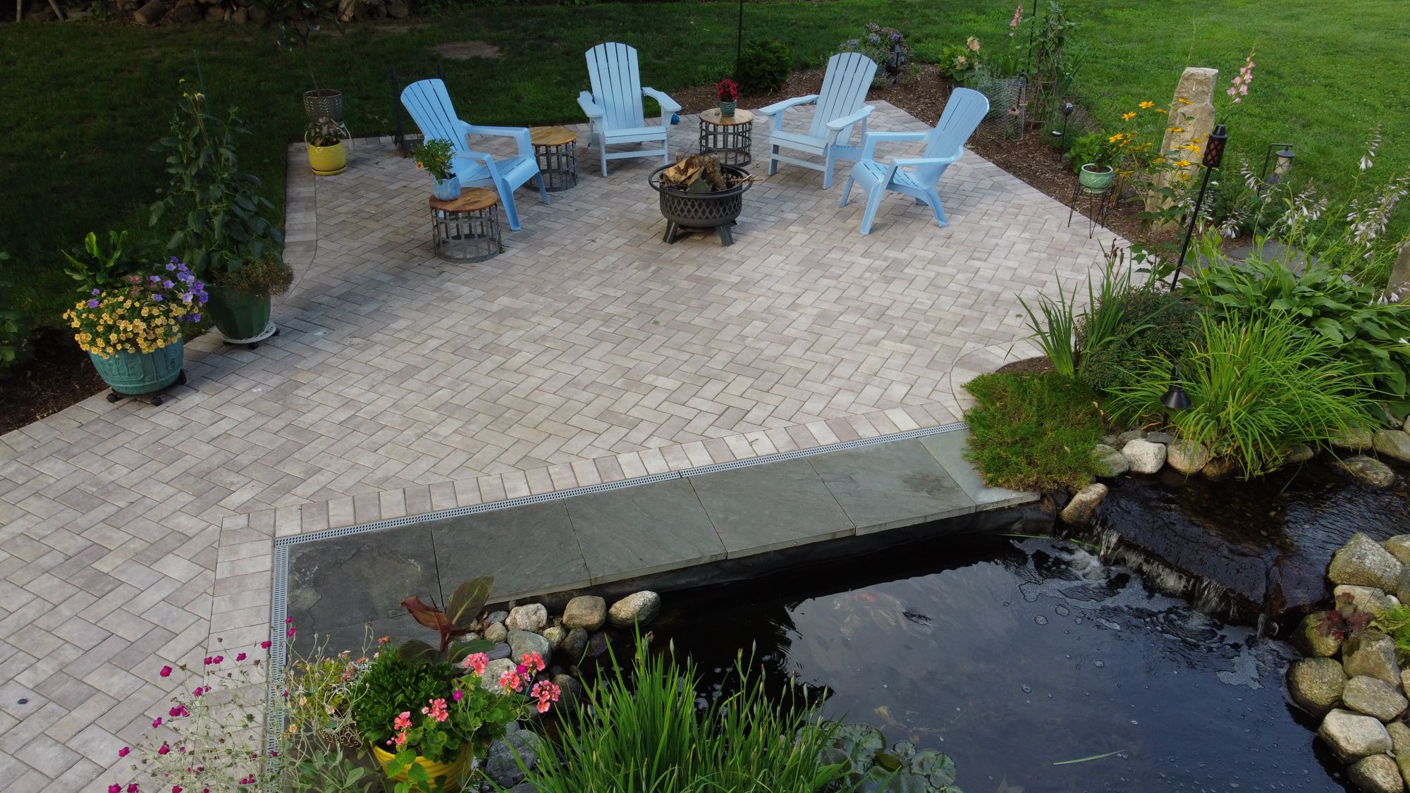 Arnold Ave project; paver patio with koi pond, Adirondack chairs and firepit