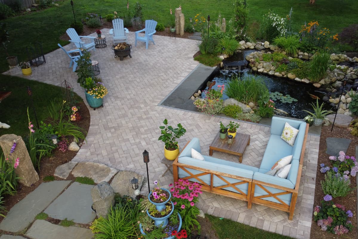 Arnold Ave project; pavers and natural stone with koi pond, sectional, Adirondack chairs and beautiful landscaping