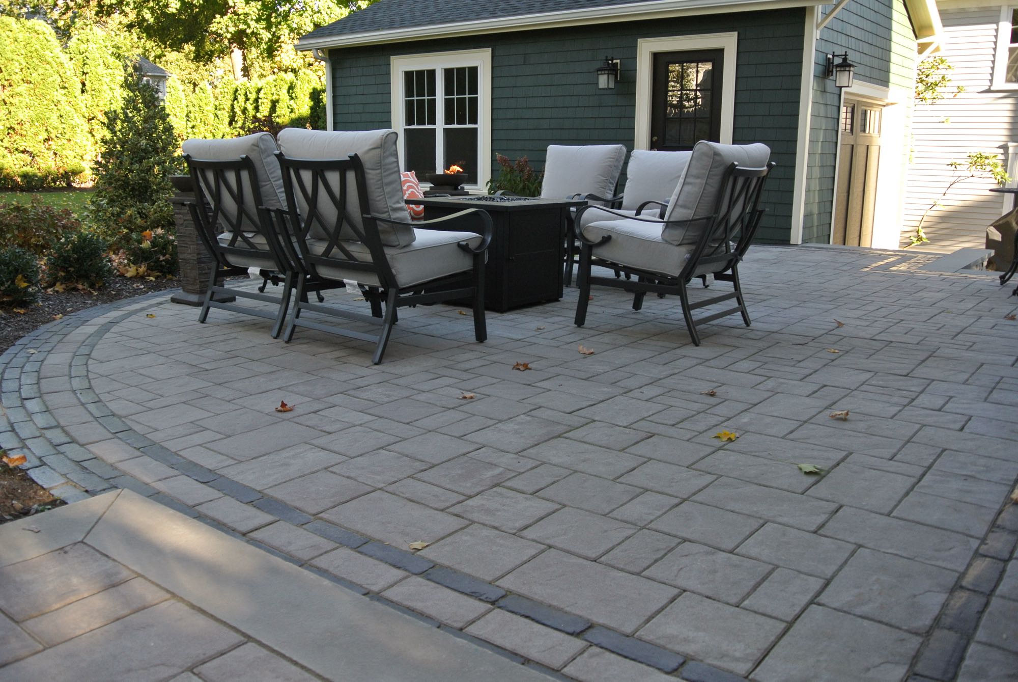 Greene Street project; small paver patio with fire pit and cushioned seating in front of stylish shed/garage