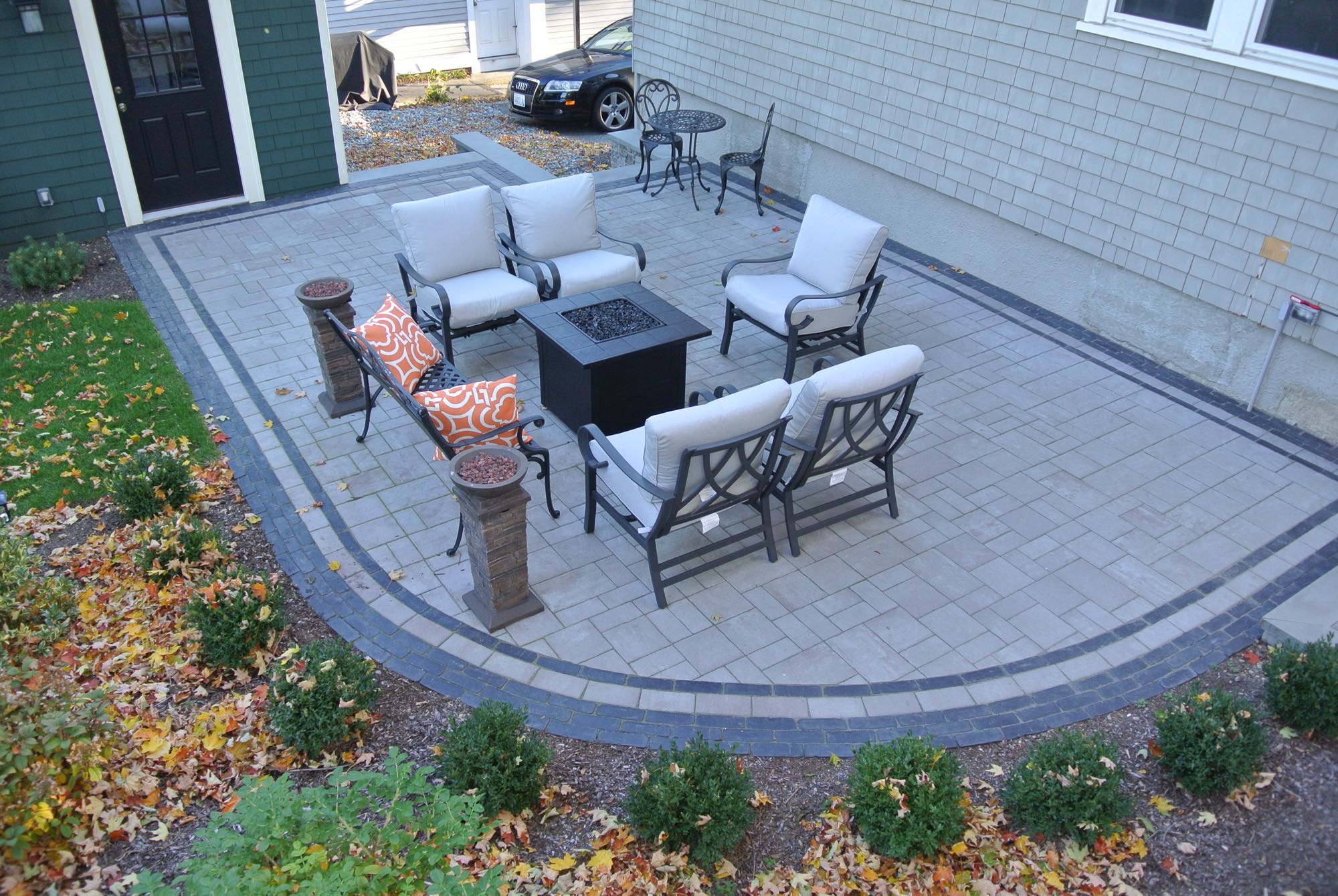 Greene Street project; small paver patio with fire pit and cushioned seating and bistro set with car in background