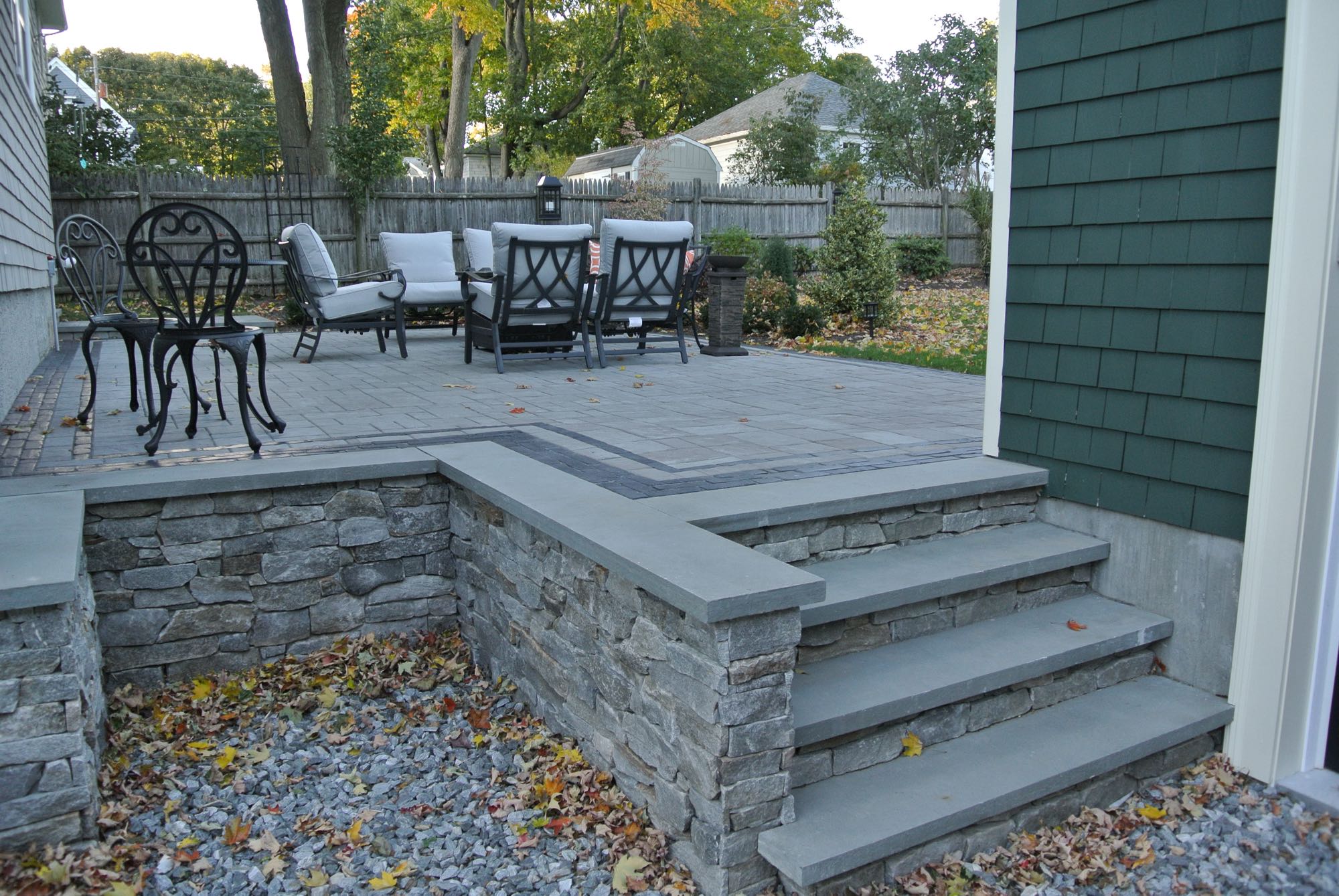 Greene Street project; stone slab stairs leading to small paver patio with fire pit and cushioned seating and bistro set