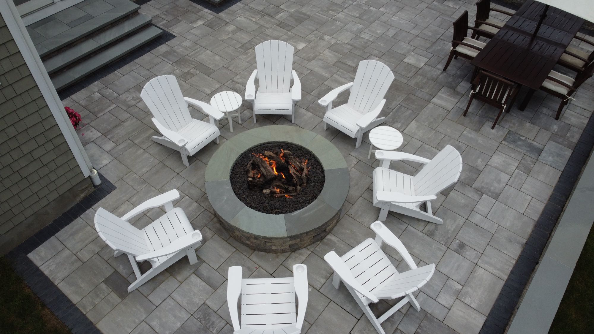 Half Mile road project; small paver patio with seven Adirondack chairs around fire pit