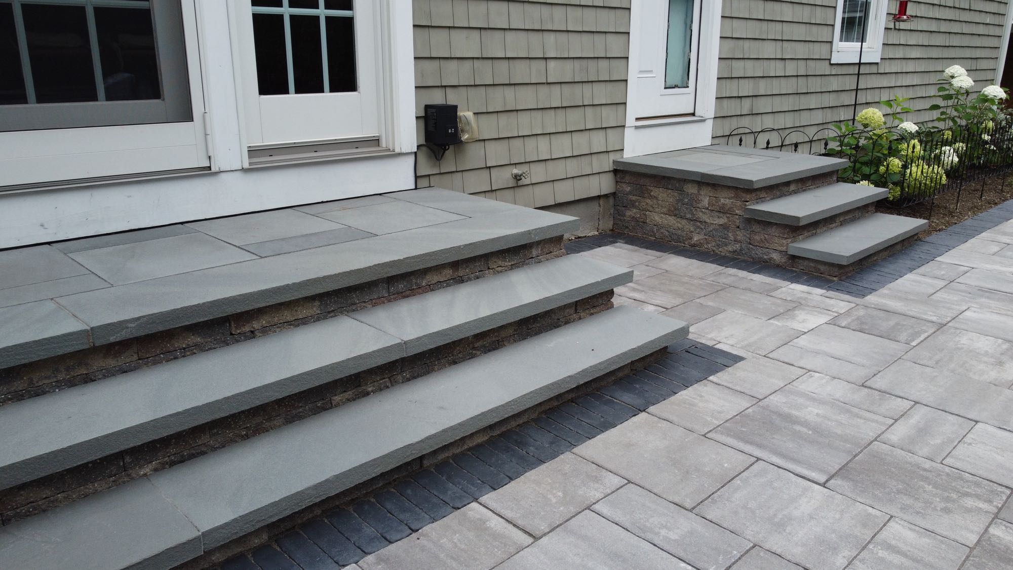 Half Mile road project; small paver patio with two stone and paver stairs leading to two back doors