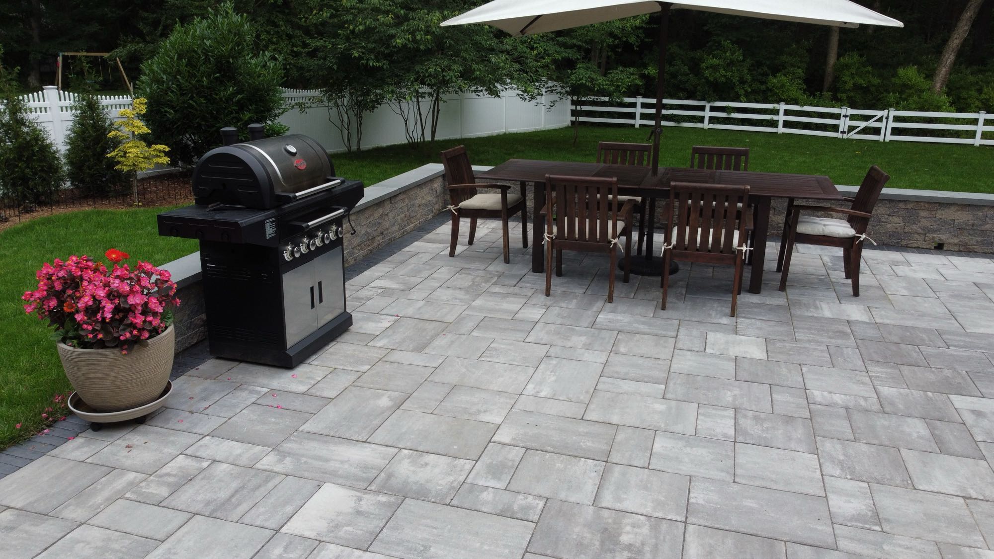 Half Mile road project; small paver patio with stone wall, grill, and dining set