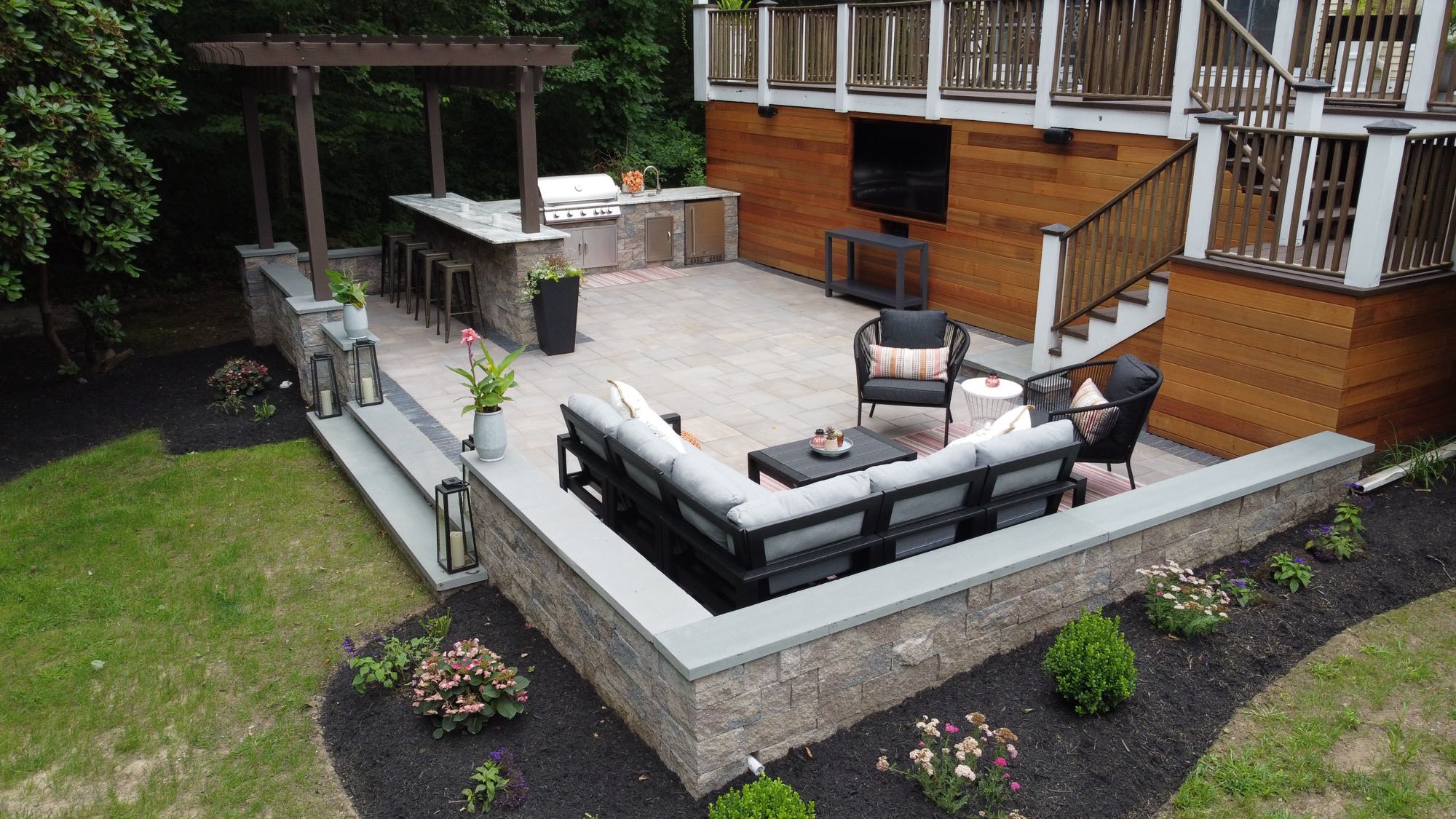 Howland Road project; paver patio entertainment area with stone wall, bar, and grill area in front of a large wooden deck