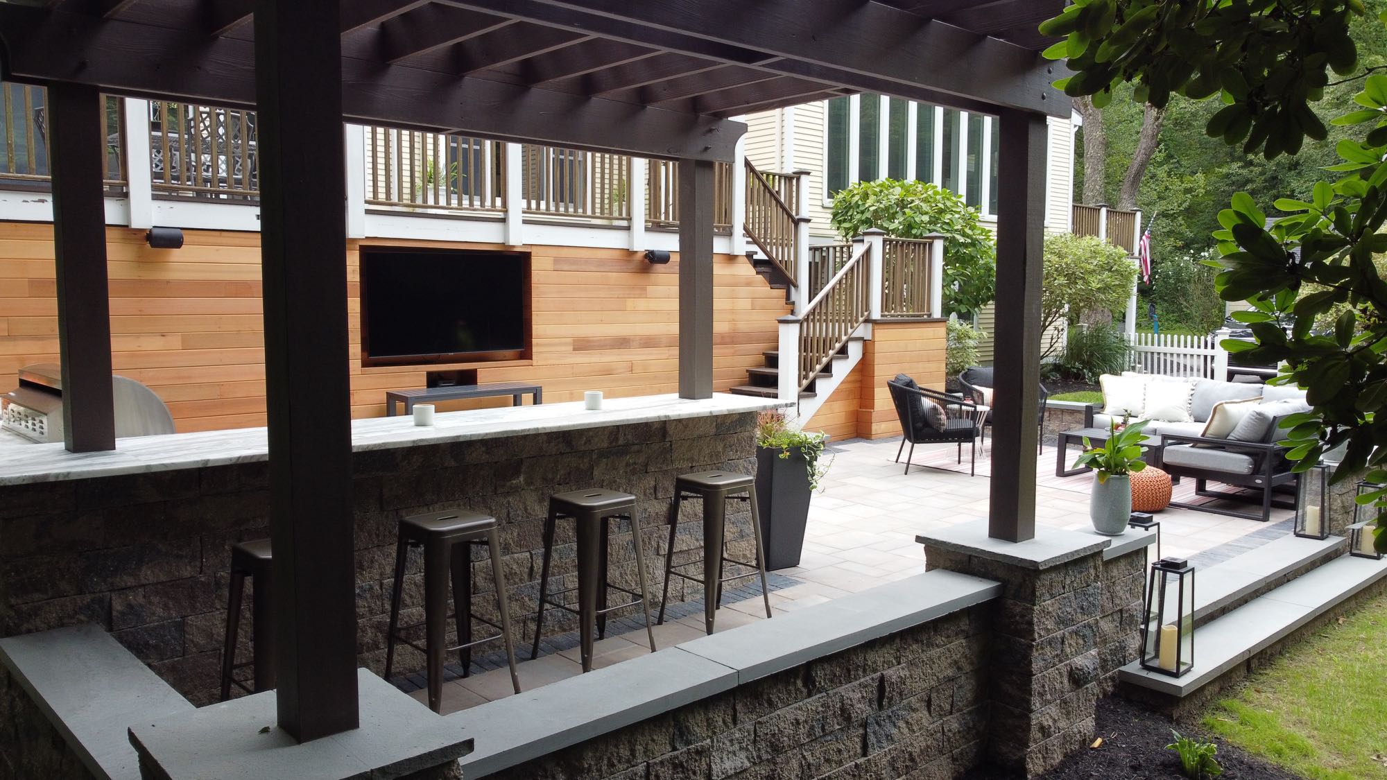 Howland Road project; paver patio entertainment area with barstools, pergola, outdoor TV and seating area in front of large wooden deck