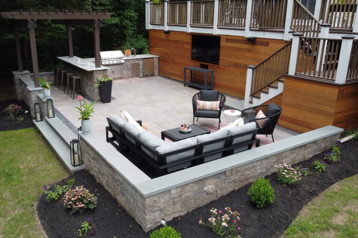 Howland Road project; paver patio entertainment area with stone wall, bar, and grill area in front of a large wooden deck