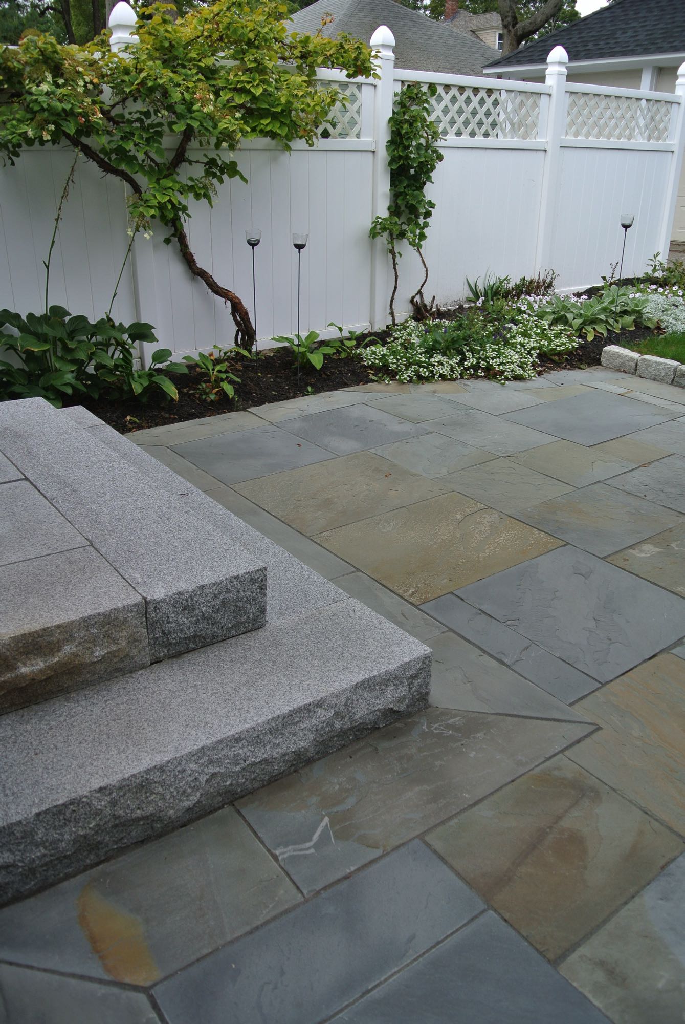 Prospect Street project; natural stone patio and stone steps in front of white privacy fence