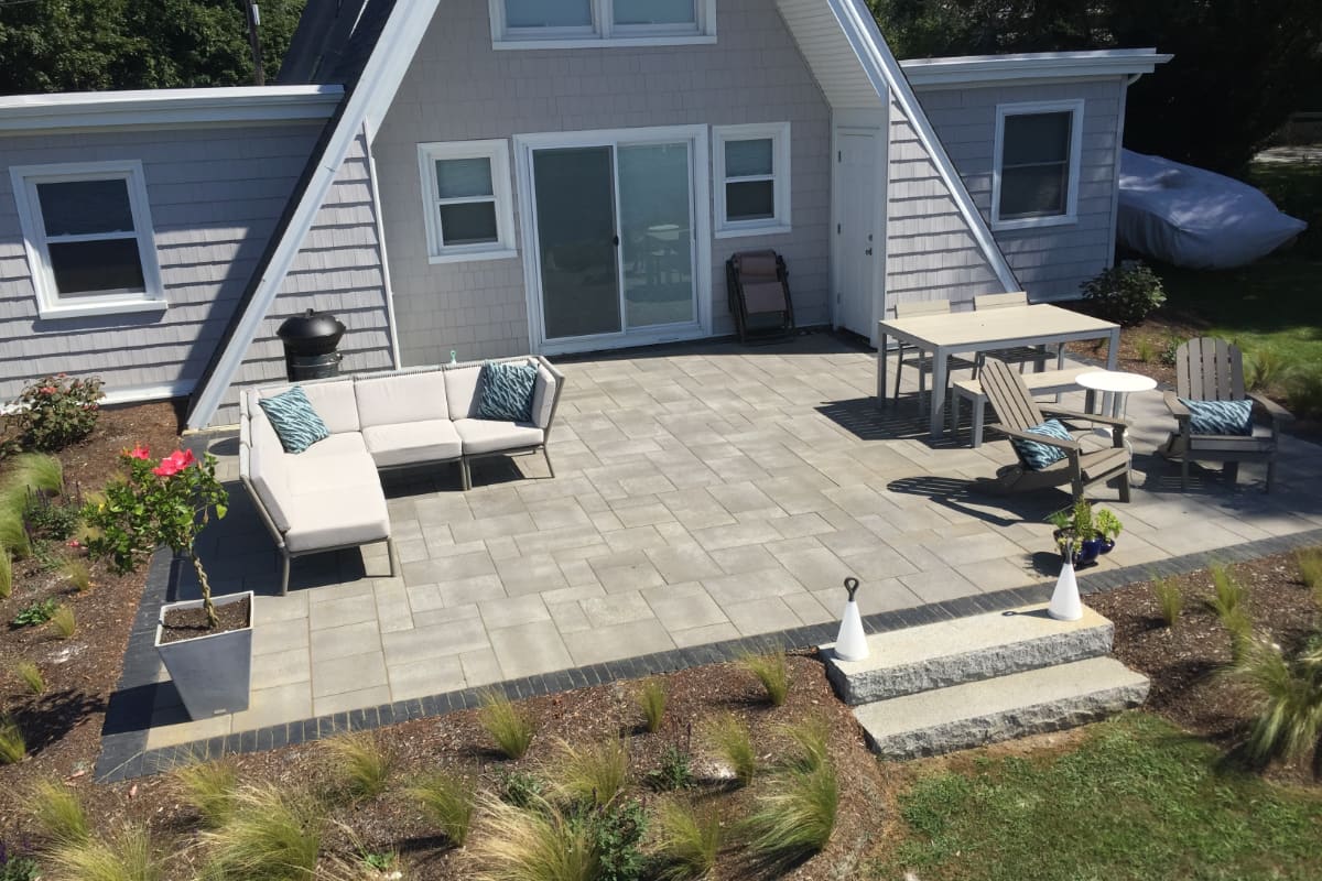 Sapowet patio project; view of A-frame house with small paver patio and natural stone steps with nice patio furniture