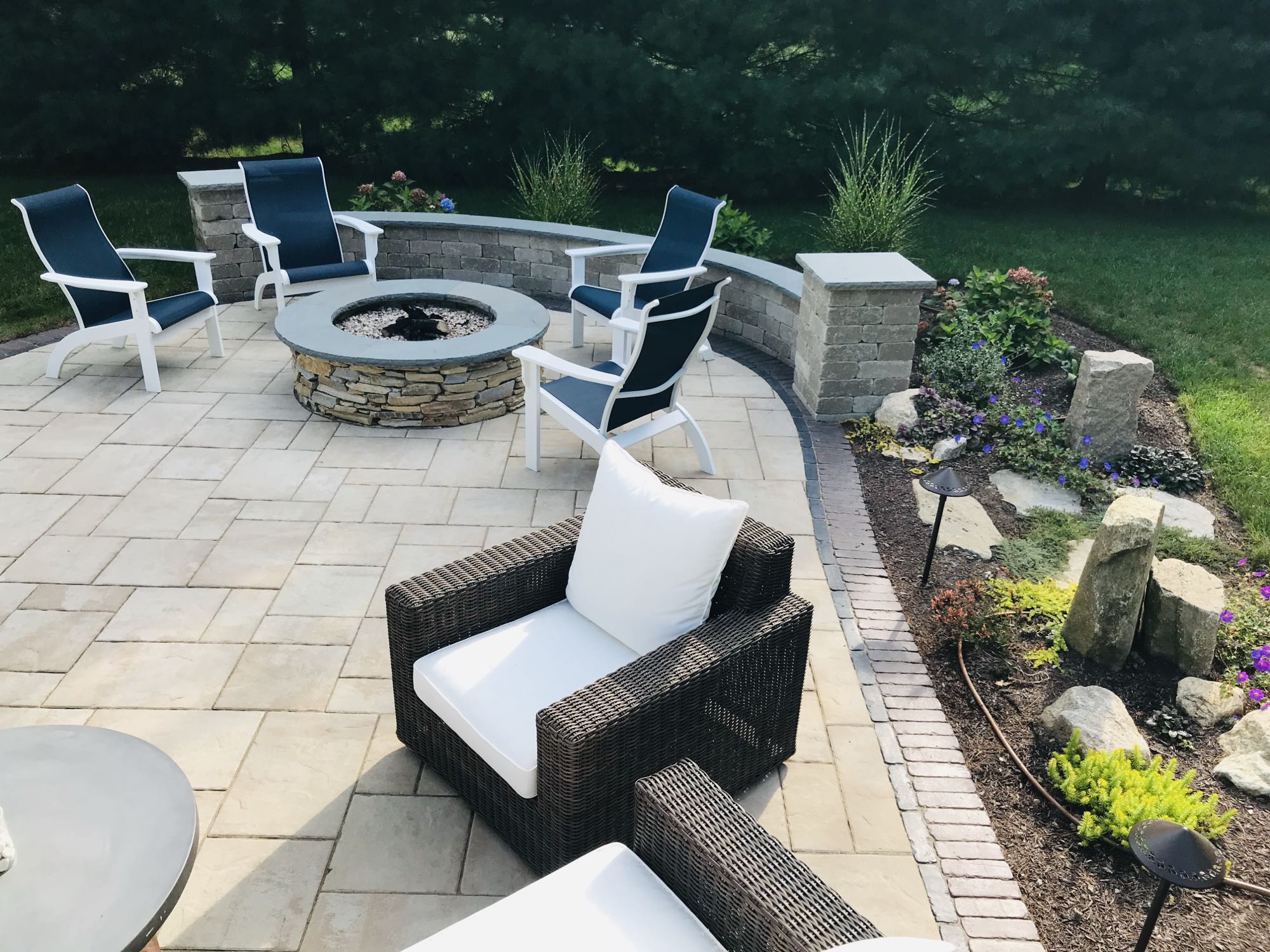 Sylvan Court project; paver patio with short wall around fire pit area and natural stone steps to lawn