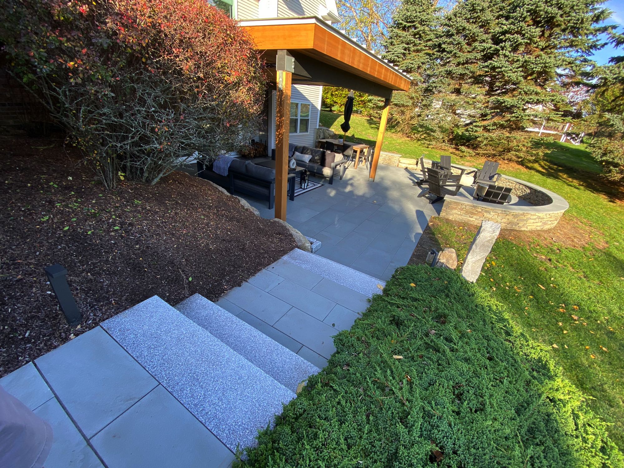 Wild Rose project; large stone patio with border wall, covered seating area, fire pit, and large stone slab stairs