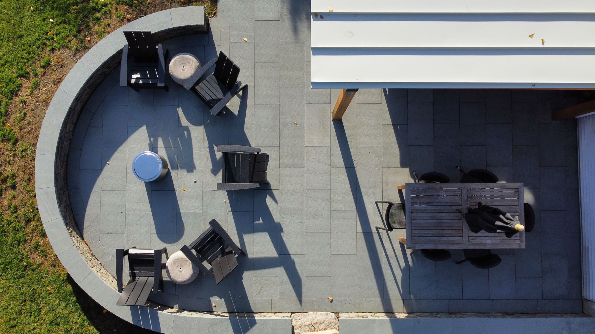 Wild Rose project; overhead view of large stone patio with border wall, covered seating area, fire pit, and dining set