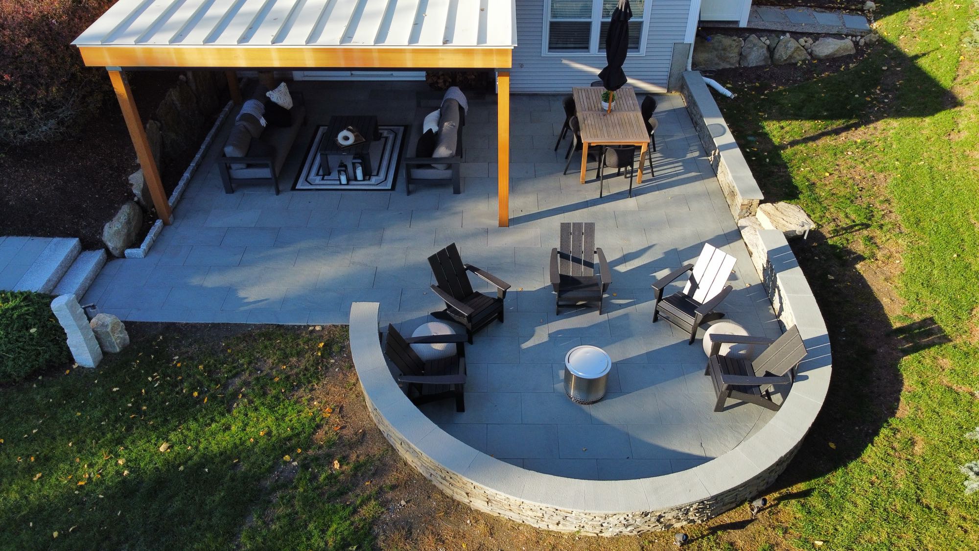 Wild Rose project; large stone patio with border wall, covered seating area, fire pit, and large stone slab stairs