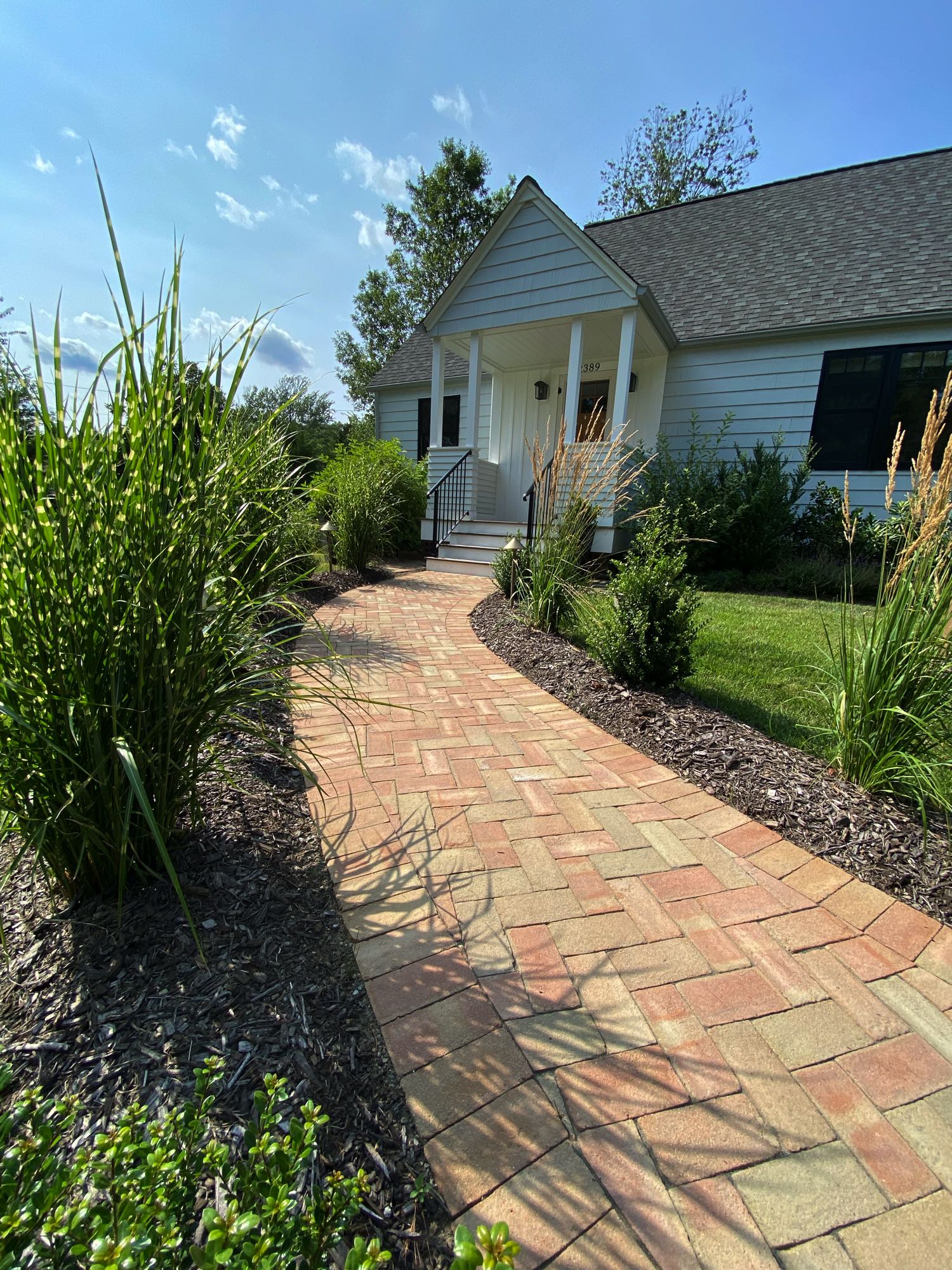 Division Rd project; brick paver walkway in herringbone pattern bordered by mulch and bushes