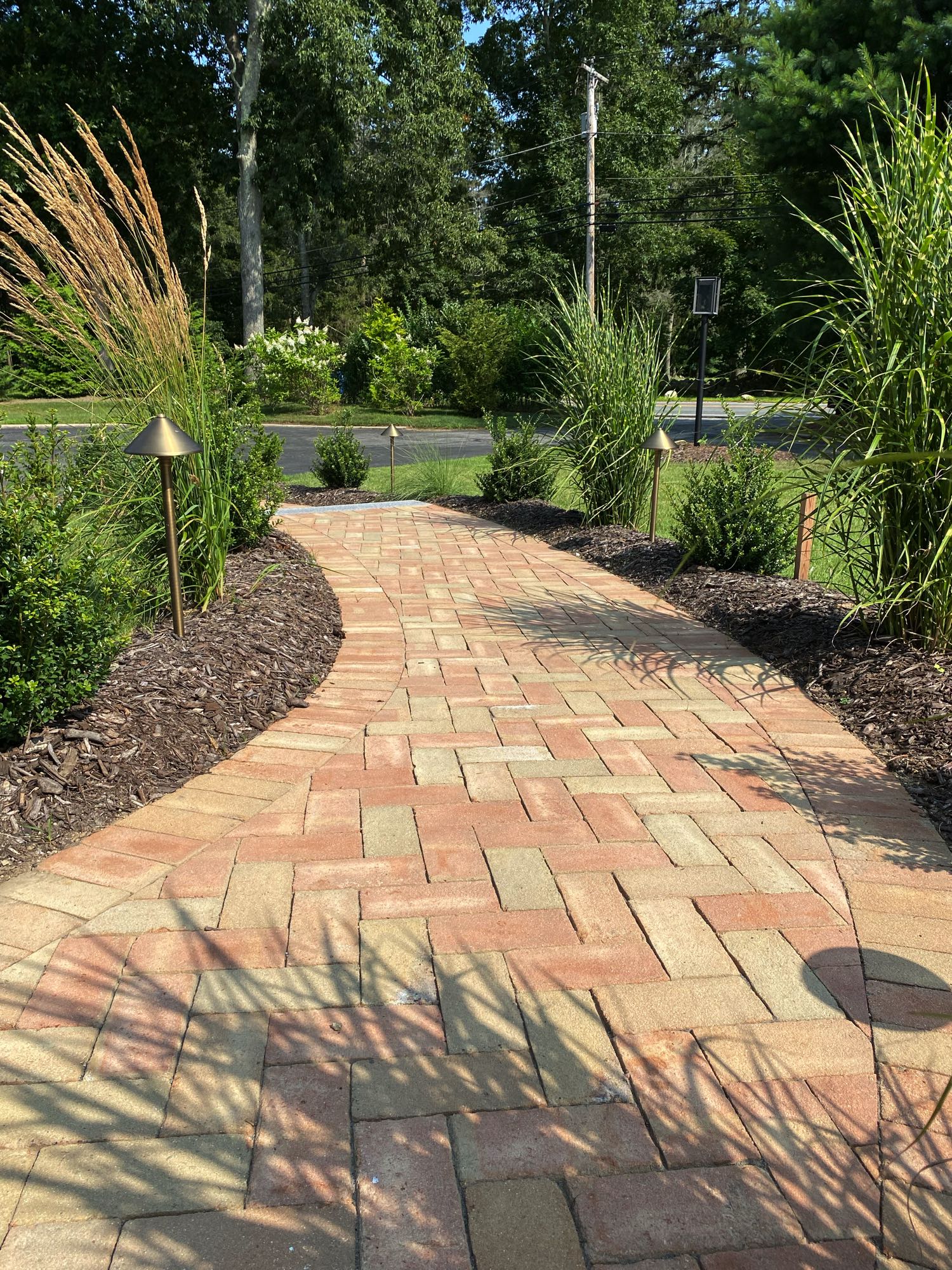 Division Rd project; brick paver walkway in herringbone pattern bordered by mulch and bushes