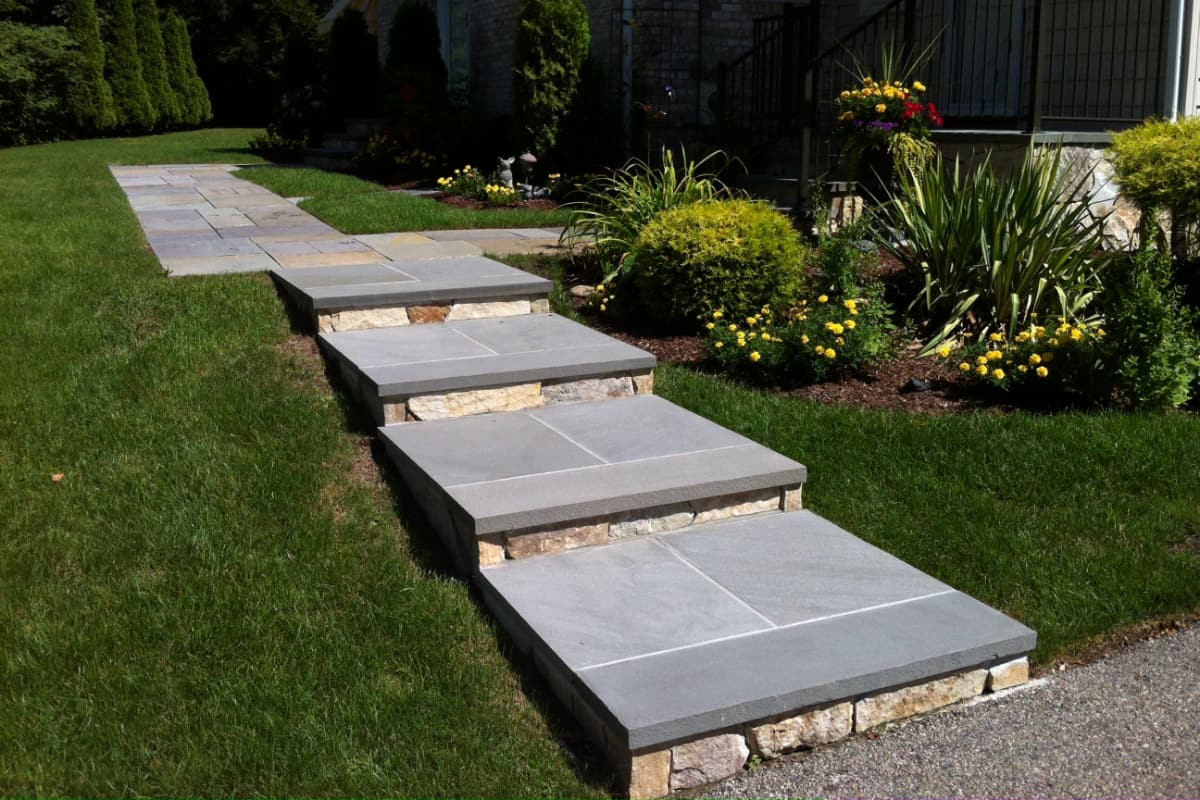 large stone slab natural stone stairs leading from walkway to driveway