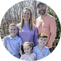 family with parents and three young children smiling at camera