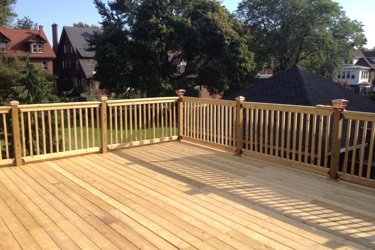 large wooden deck with a view of several houses in a neighborhood