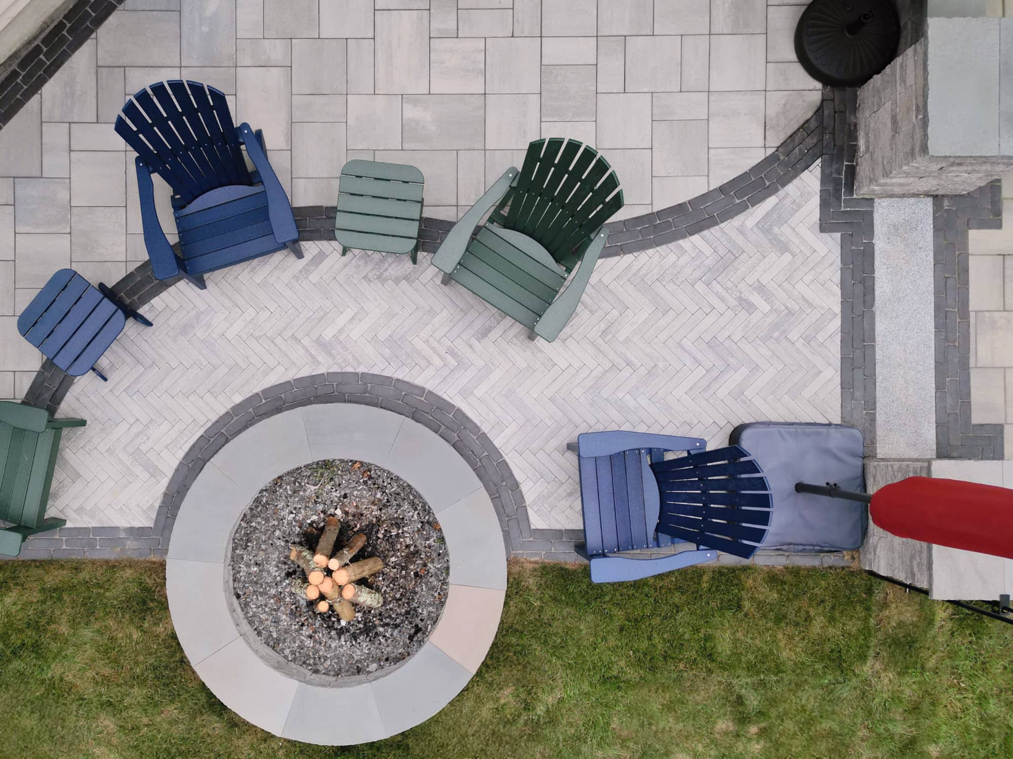 overhead view of a paver stone patio with multiple patterns and a paver fire pit with Adirondack chairs