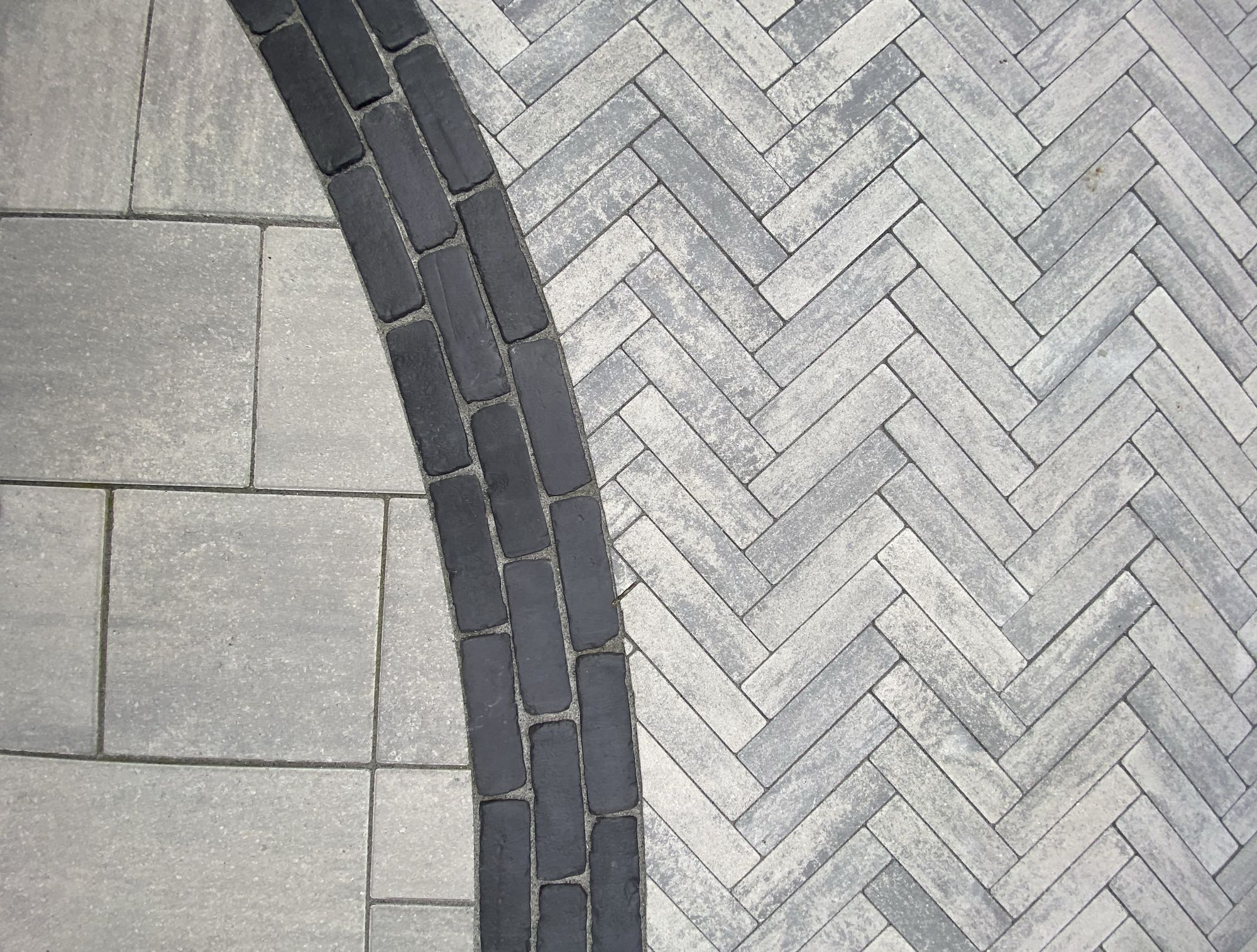 paver stones tiled one one side and herringbone pattern on the other with a brick rounded border