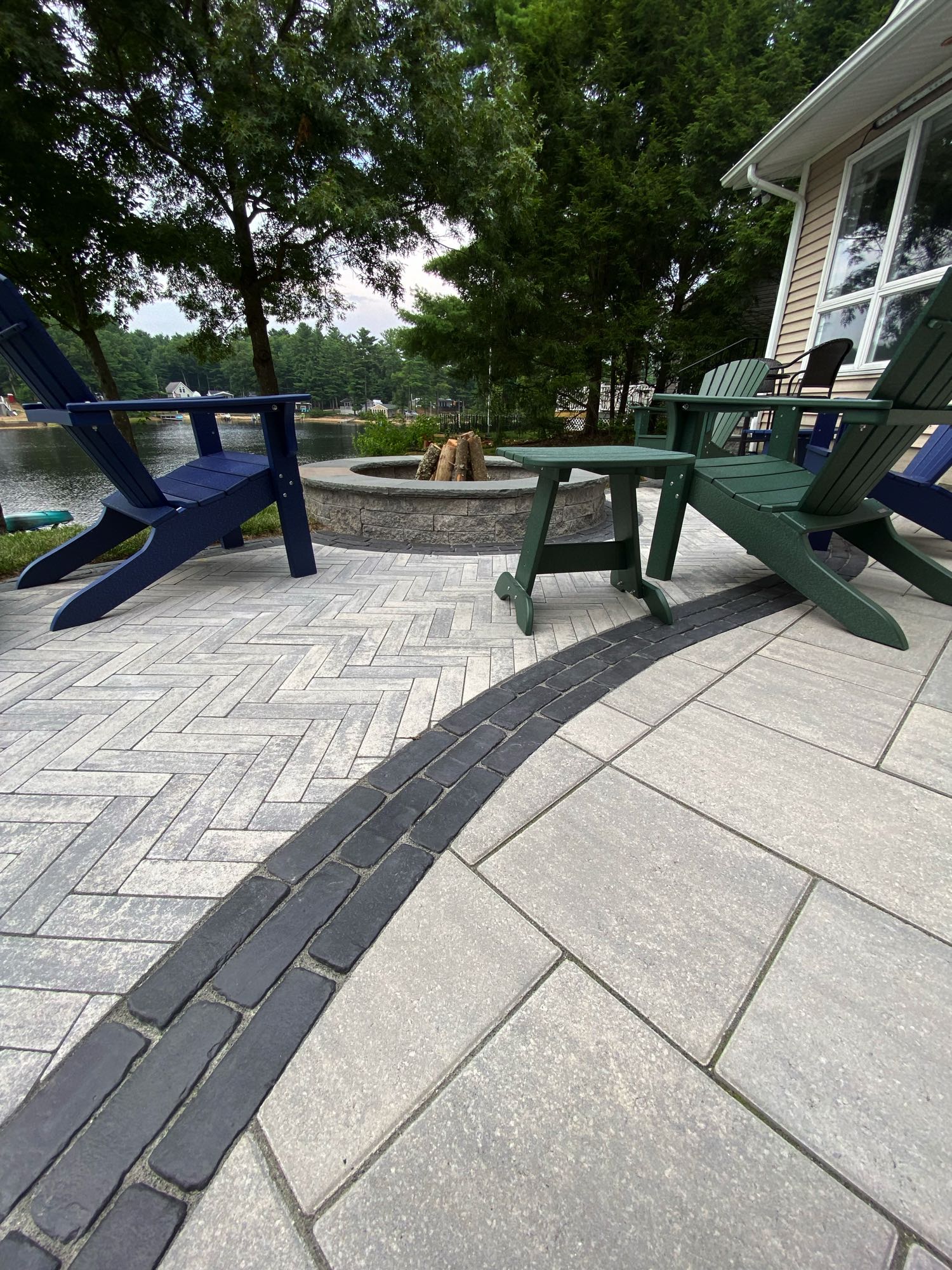 paver stone patio with multiple patterns and a paver fire pit with Adirondack chairs